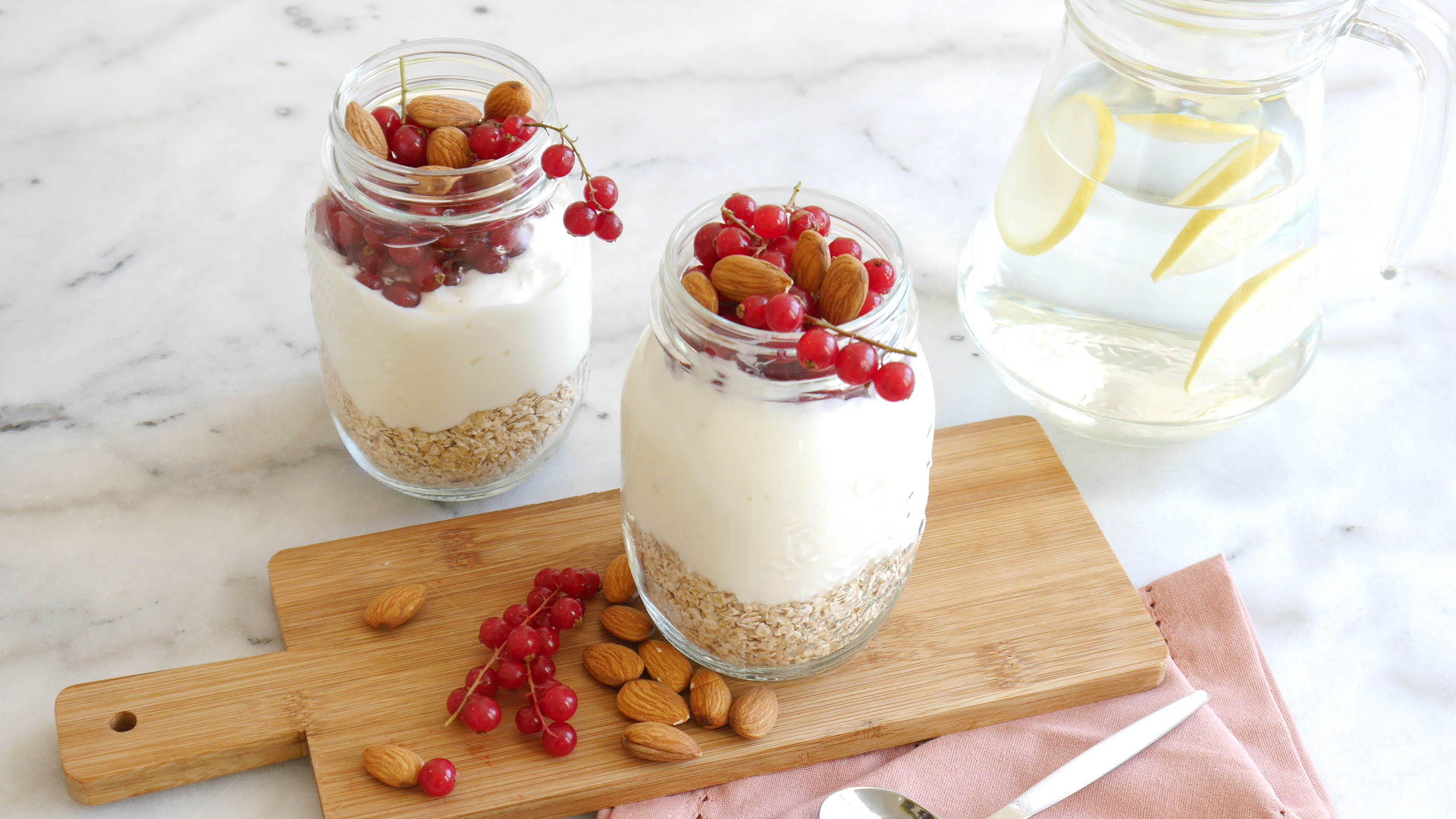 Deux yaourts dans des pots en verre avec des groseilles et des amandes Deux yaourts dans des pots en verre avec des groseilles et des amandes